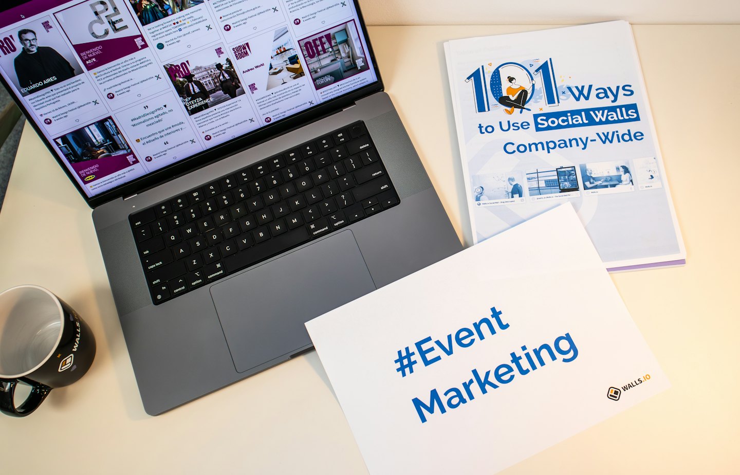 Laptop with social media feed and marketing documents on a desk.